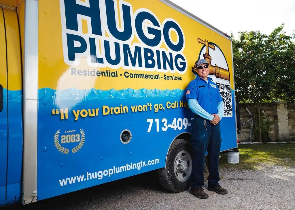 A Hugo Plumbing technician beside a service truck